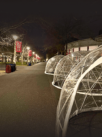 Clear outdoor igloo tents installed on a university campus for a winter-time student event.